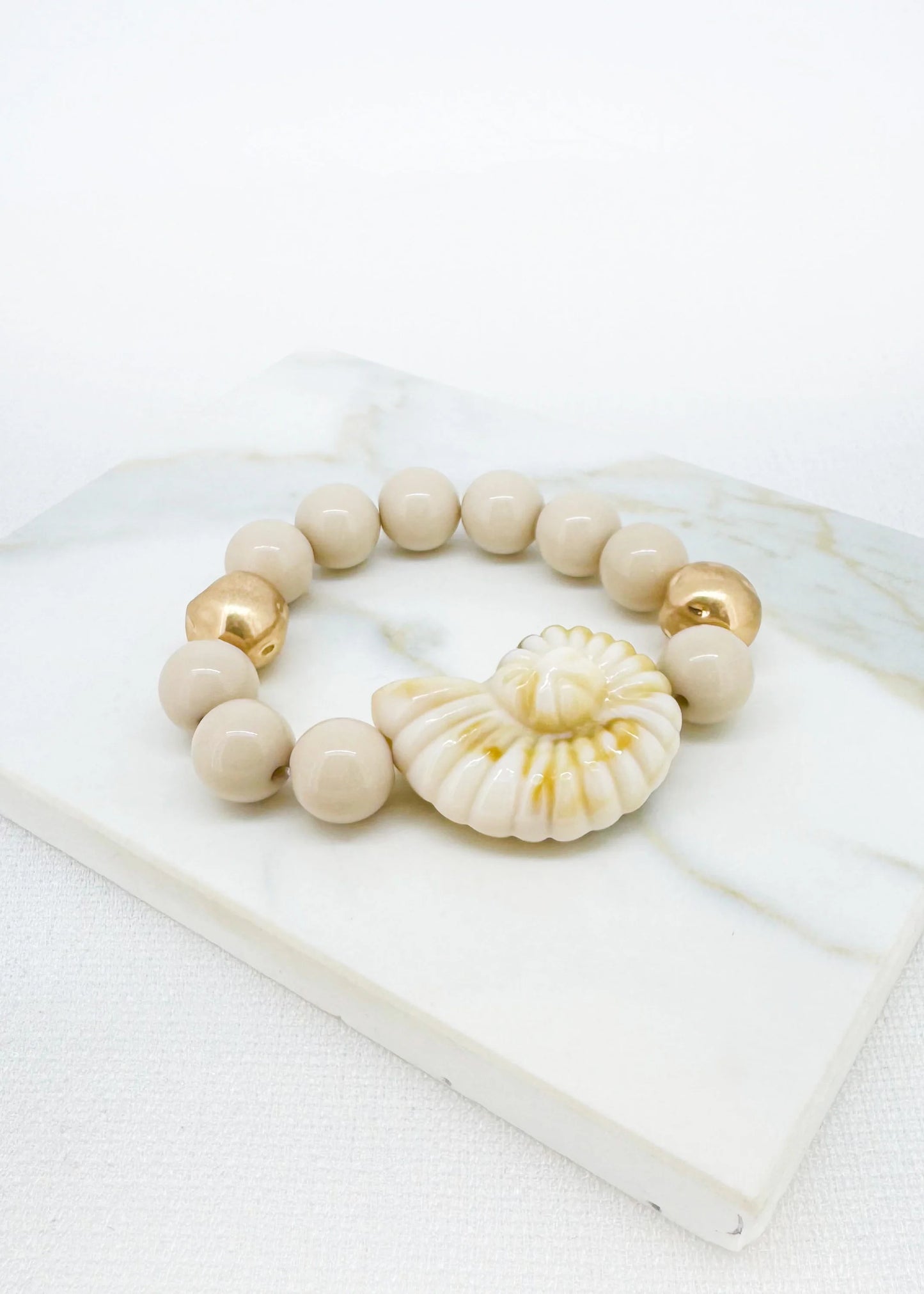Beige and gold bead bracelet with fossil pendant